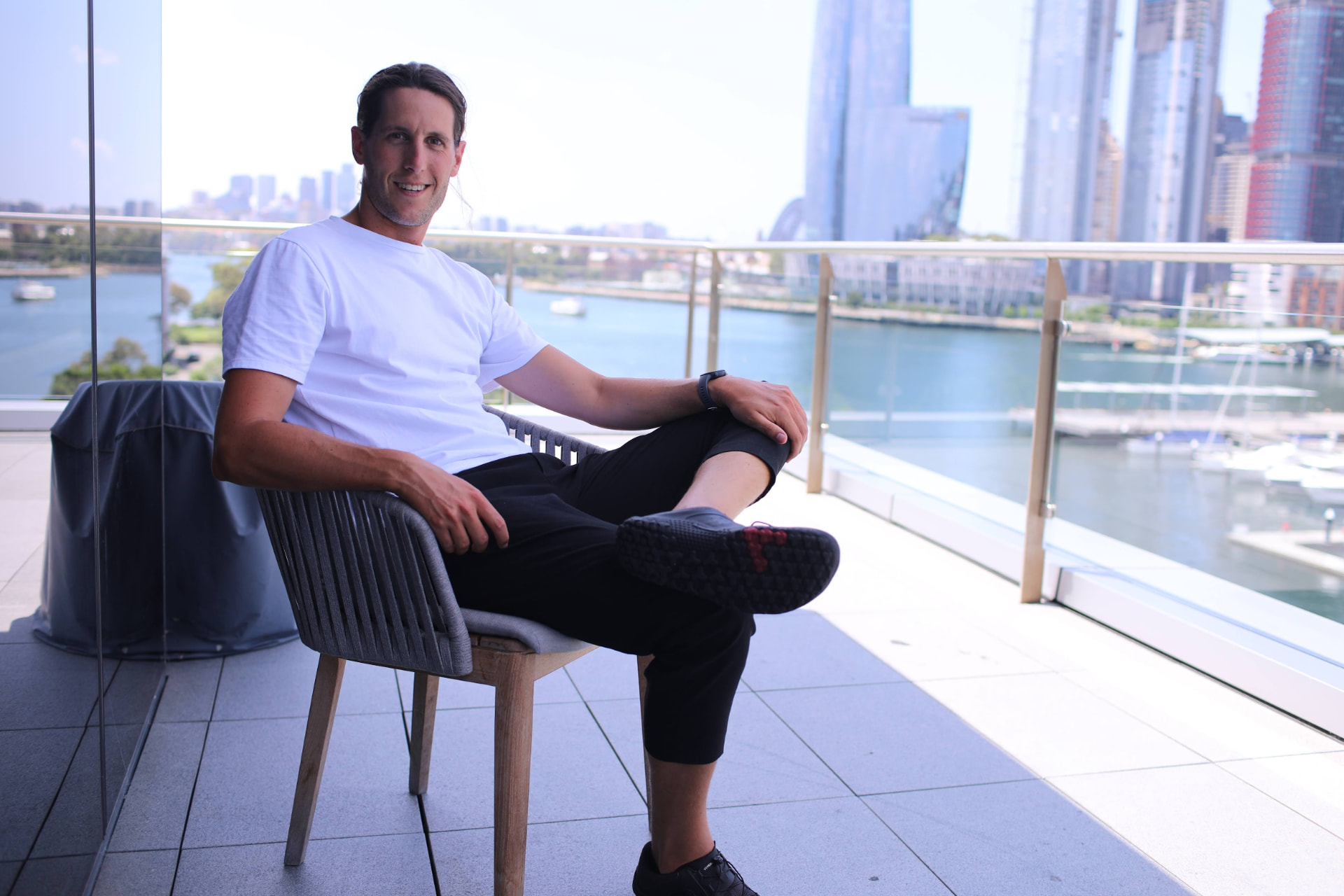 Sean sitting on a balcony above the Sydney harbour skyline